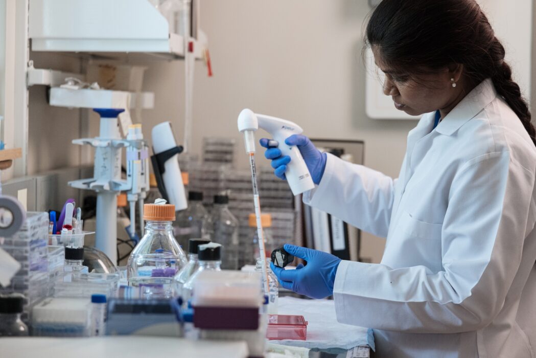 Female scientist wears white lab coat as she works in the lab.