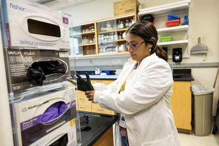 A scientist wearing a white lab coat performs a test in a lab at Texas Biomed.